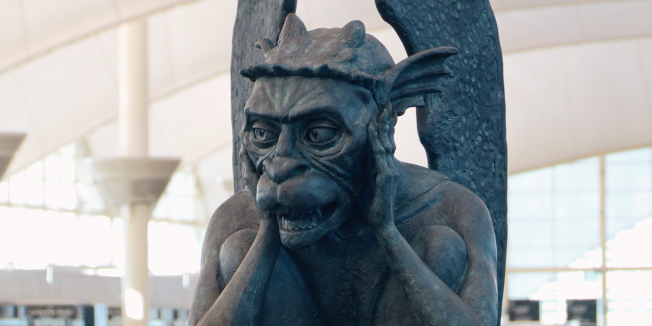 Gargoyle at Denver International Airport has its hands on the sides of its face.