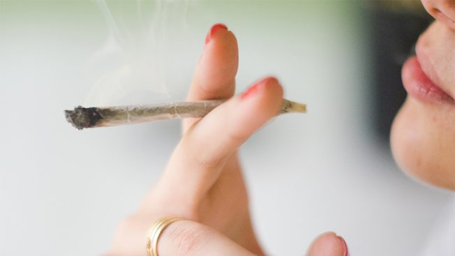 A woman is taking a drag from a cannabis cigarette