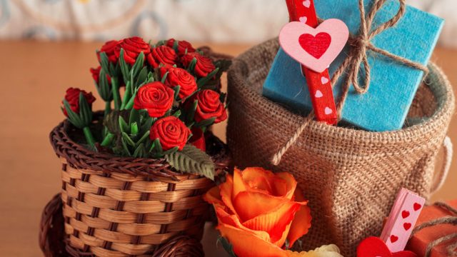 A gift basket; there is a basket of roses; a basket with a present wrapped in blue paper; as well as an orange flower