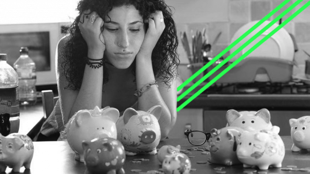 A woman sits hunched over, looking upset, and staring at piggy banks.