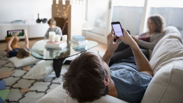A family using smart devices in a living room for a story on broadband subscriptions and smartphones