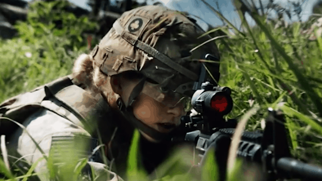 Soldier in dense foliage aiming a gun