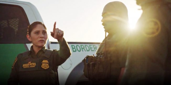 Female U.S. Customs and Border Protection agent pointing something out to her colleagues.