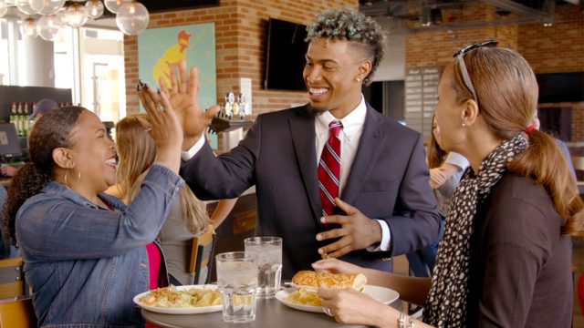 Francisco Lindor high-fiving a woman at a table in a restaurant