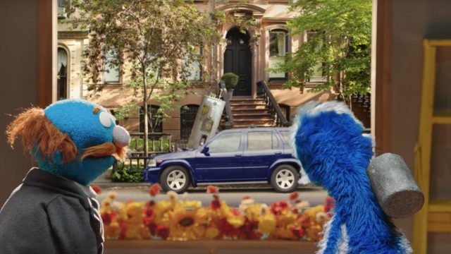 Muppets look out a window at a blue car