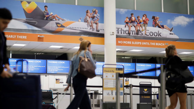 A traveler walks past Thomas Cook signage in an airport.