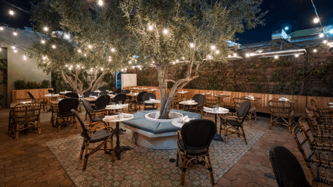 the backyard of a restaurant with lights in trees and tables and chairs