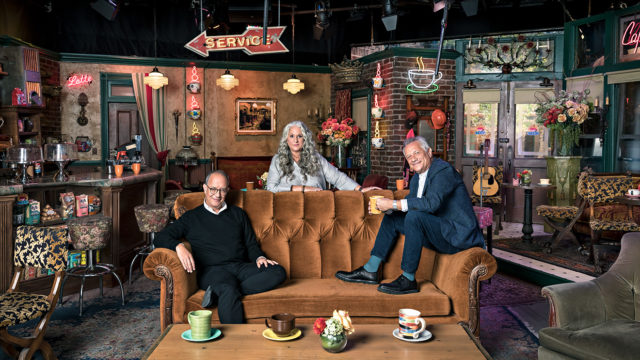 Friends creators David Crane, Marta Kauffman and Kevin Bright gather around the orange couch from Central Perk at the NYC pop-up museum.