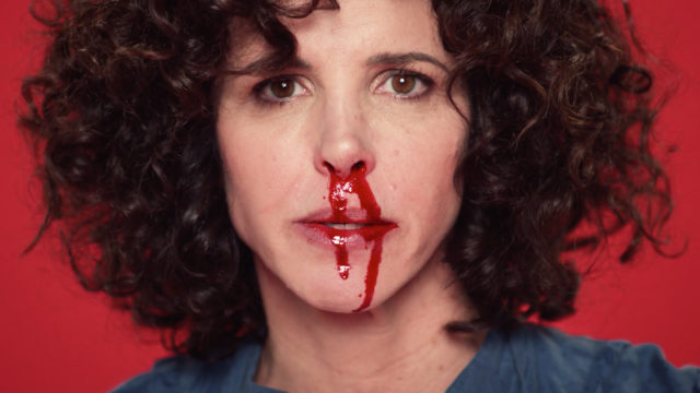 a woman with lots of curly hair having a nosebleed