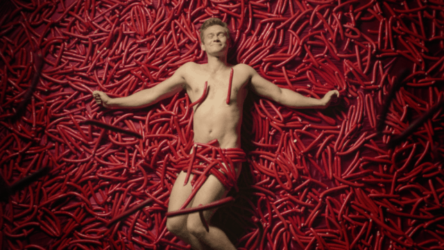 Image from a Danish anti-binge drinking PSA of man lying in a pile of sausages