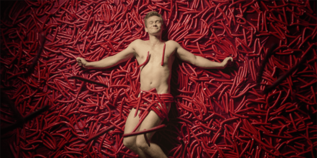 Image from a Danish anti-binge drinking PSA of man lying in a pile of sausages