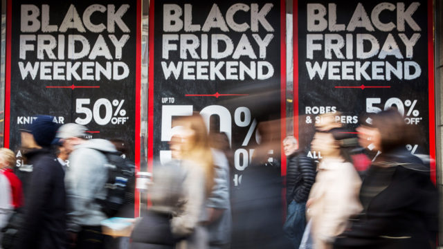 People walking with Black Friday promotional posters in the background