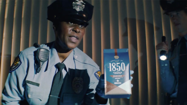 A police officer holding up Folgers 1850 coffee.