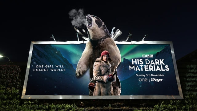 A billboard ad for His Dark Materials shows protagonist Lyra and an armored polar bear who appears to breathe