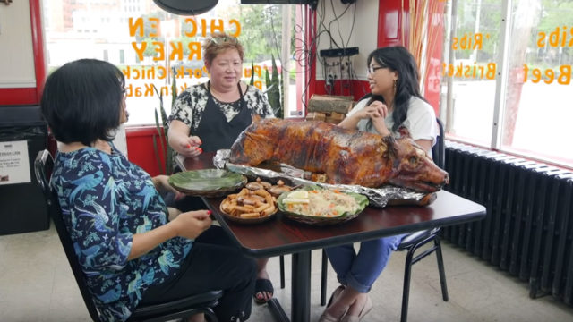 three women sit around a table with lechon and other food
