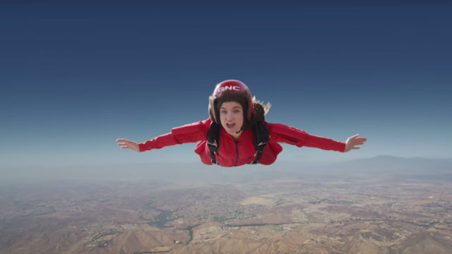 woman skydiving in a red jumpsuit and gnc helmet