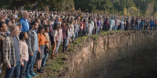 people standing at the edge of a giant hole