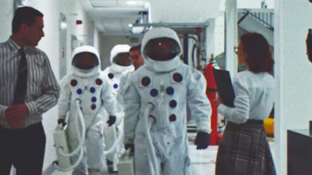 Astronauts walk toward the camera in footage that seems to date from the 1960s