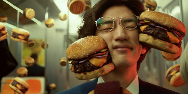 Burgers collide with a subway rider's face in an ad for Postmates