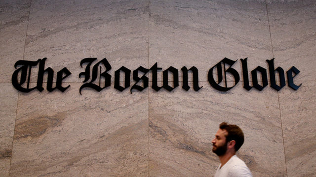 A man in front of The Boston Globe logo