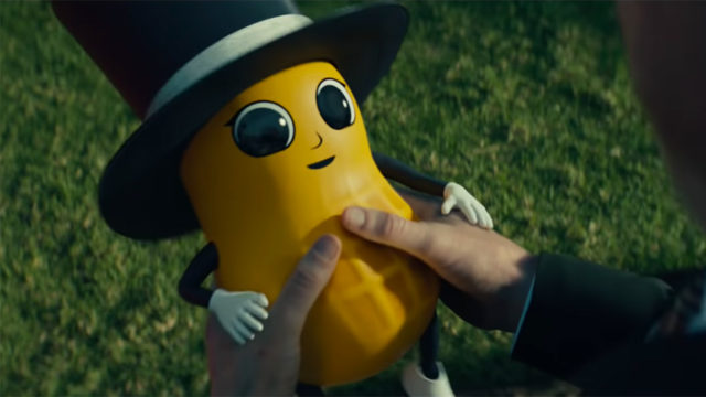 A baby version of Mr. Peanut looks up at someone holding him