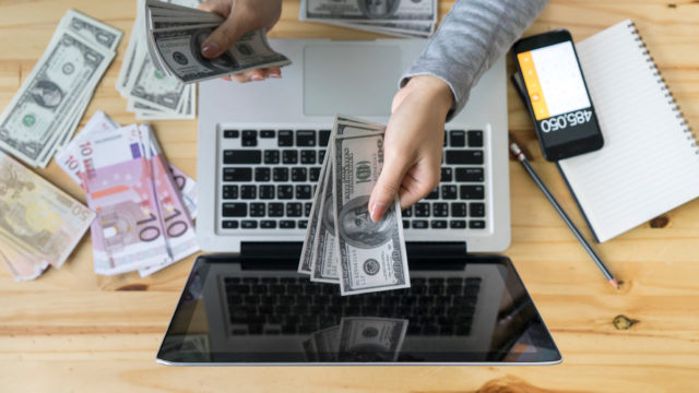a person handing money to a computer screen