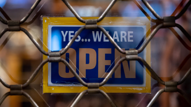 Open for business sign behind chain-link fence