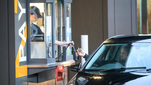 a fast food worker handing over food at a drive through window
