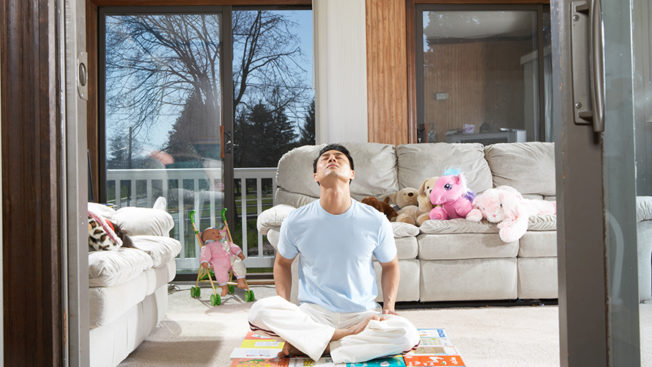A man sitting on a living room floor meditating