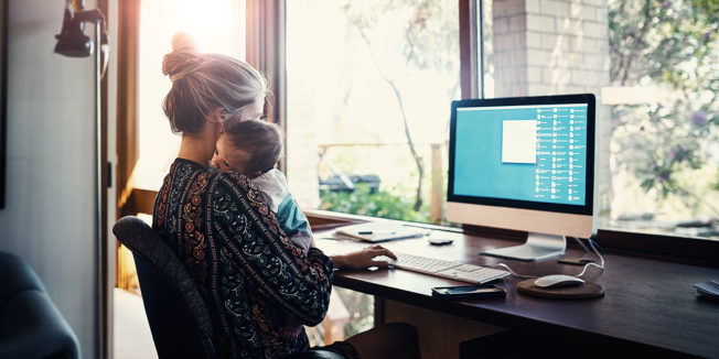 woman holding child while working at a computer