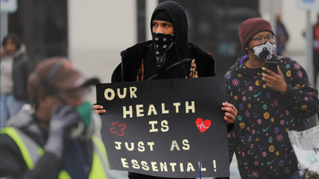 Chris Smalls holding a sign that says, 'Our health is just as essential'