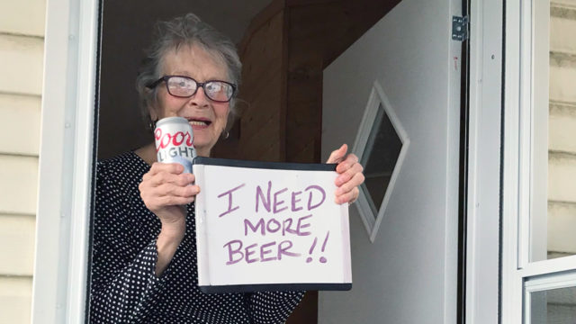 Woman holding a Coors Light and a sign that says, 'I need more beer'