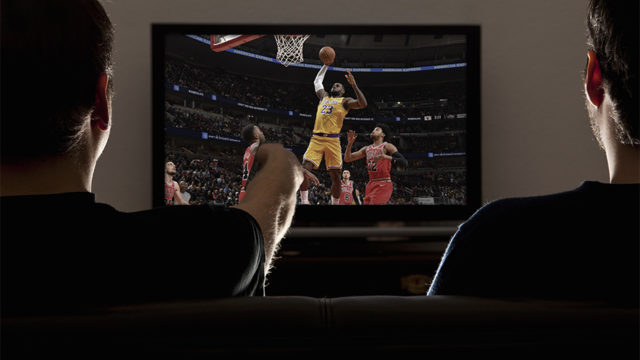 People watch Lakers basketball on a TV.