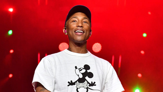 pharrell williams smiling with a red background