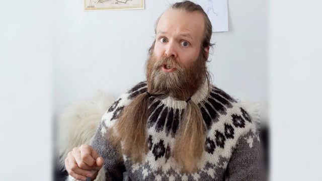 Photo of a man with a long beard held by hair ties