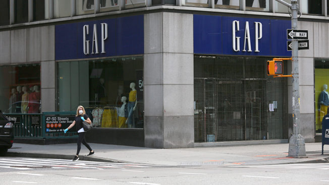 woman wearing face mask and gloves walks past a Gap store in New York City