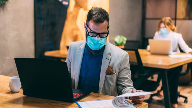 Man wearing a face mask in front of a laptop