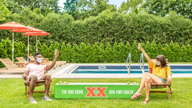Photo of the Dos Equis seis-foot cooler with two people giving cheers