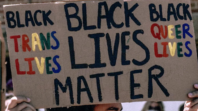 Cardboard sign that says Black Trans Lives, Black Queer Lives and Black Lives Matter