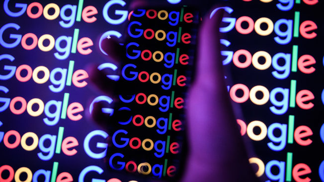 Image of the Google logo under a hand holding a smartphone
