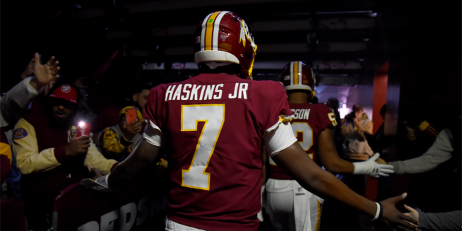 a man in a red football jersey number 7 that says haskins jr