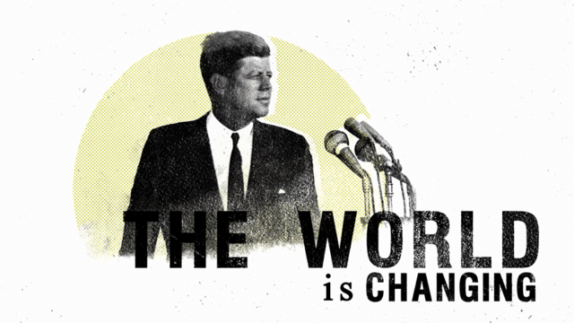 president kennedy speaking into microphones on a yellow circular background with the world The World IS Changing underneath to the right