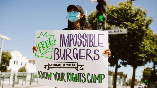 Woman holding up sign for Impossible burgers