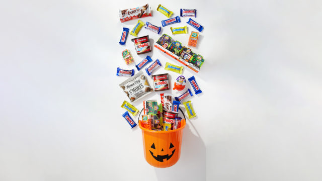 candy bars falling into a plastic jack-o-lantern bowl