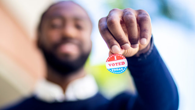 a man holding up an i voted sitcker