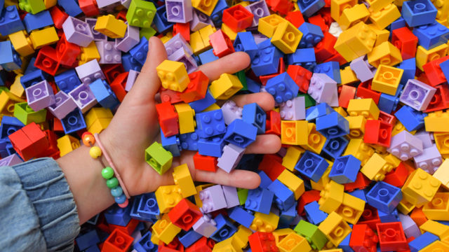 a hand dipping into a pile of lego blocks