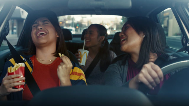 people singing passionately in a car holding mcdonald's
