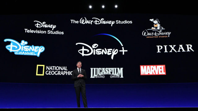 disney+, disney, pixar, marvel, the walt disney company, national geographic and lucas films logos on a screen behind a man standing on a stage
