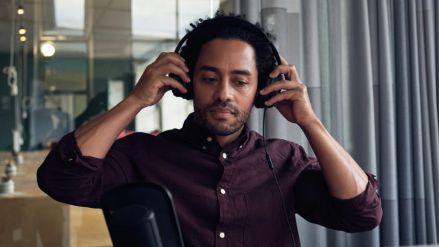 A Black audio content creator puts on headphones