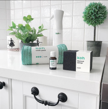 a bathroom counter with various cleaning supplies on it with plants in the background